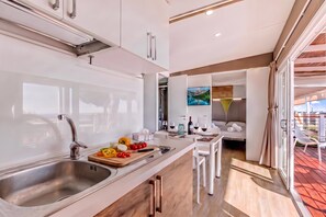 A modern kitchen with a stainless steel sink, a wooden cutting board with vegetables, and a dining area with a table and chairs.