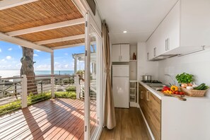 A modern kitchen with a view of the sea, a wooden deck, and a balcony.