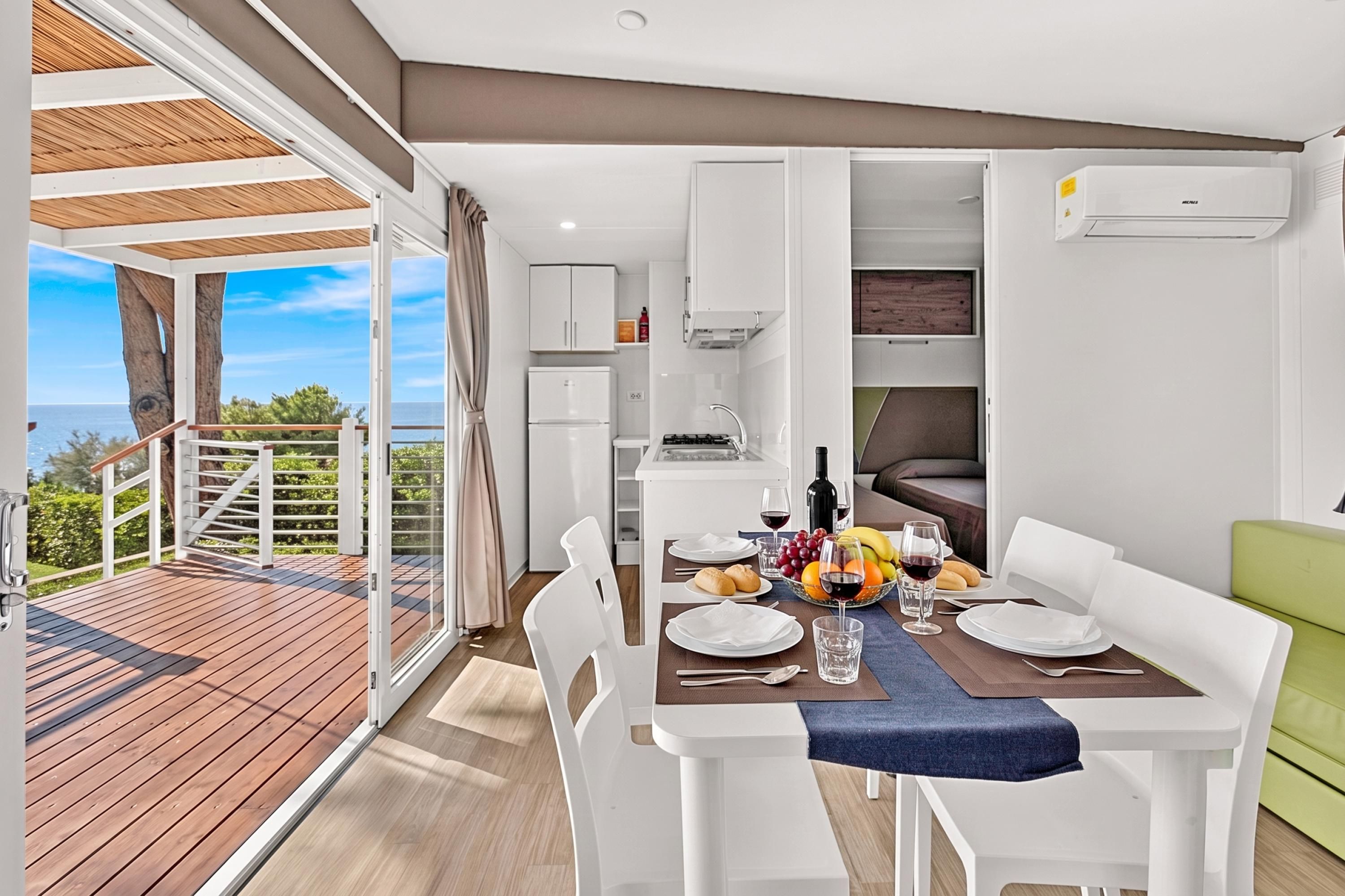 A modern dining area with a view of the sea, a kitchen, and a living area.