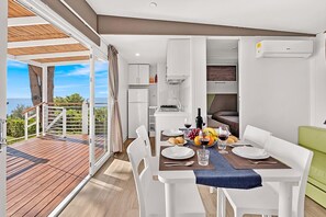 A modern dining area with a view of the sea, a kitchen, and a living area.