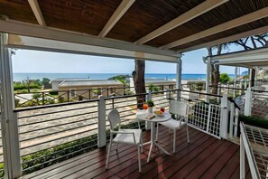 Un espacio al aire libre cubierto con una mesa, sillas y vistas al mar, además de una terraza de madera.