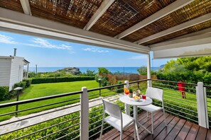 A balcony with a table and chairs, overlooking a green landscape and the sea. - Sea View - 40 Parallelo - Superior+ 18, Marina di Camerota, Italy (Marina di Camerota)