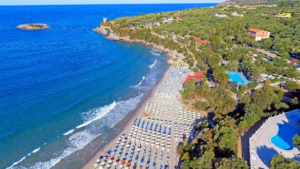 Vue aérienne d’une zone côtière comprenant une plage, une piscine et un ensemble de bâtiments.