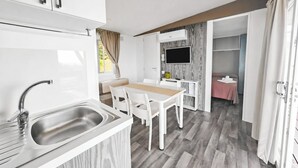 Une petite cuisine équipée avec un évier et un coin repas comprenant une table et des chaises.