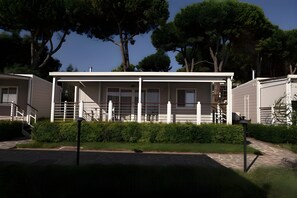 A row of modern, single-story cabins with a covered porch, a stone pathway, and a well-maintained hedge in front. - Sea View - 40 Parallelo - Superior+ 17, Marina di Camerota, Italy (Marina di Camerota)