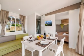 A modern room with a dining table set for two, a sofa, a TV mounted on the wall, and a window with curtains. - Sea View - 40 Parallelo - Superior+ 17, Marina di Camerota, Italy (Marina di Camerota)
