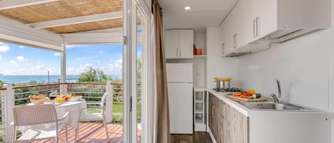 Une cuisine compacte avec vue sur la mer, un coin repas avec une table et des chaises, et une terrasse en bois.