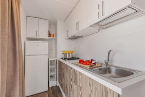 Cozinha moderna com armários brancos, pia de aço inoxidável e fogão embutido.