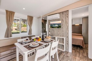 A dining area with a table set for two, a television mounted on the wall, and a view of the outdoors through the window. - Sea View - 40 Parallelo - Superior+ 16, Marina di Camerota, Italy (Marina di Camerota)