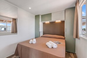 Ein Hotelzimmer mit Bett, Fenster mit Vorhängen und einer Deckenleuchte.