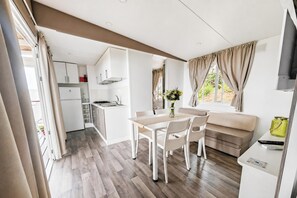 A compact kitchen with white cabinets, a dining area with a table and chairs, and a living area with a sofa and a TV. - Sea View - 40 Parallelo - Superior+ 16, Marina di Camerota, Italy (Marina di Camerota)