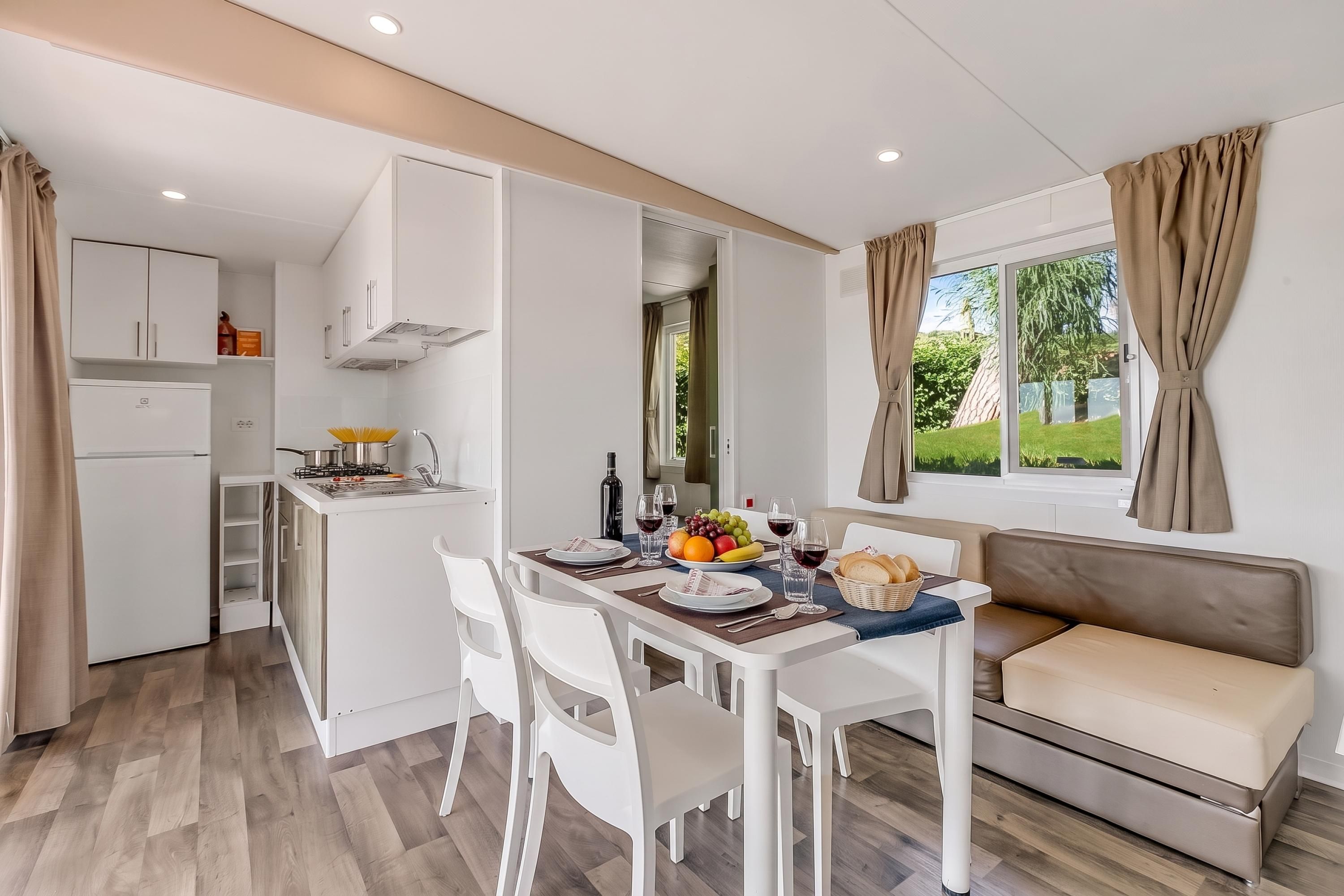 A compact living space with a kitchenette, dining area, and a window with curtains.