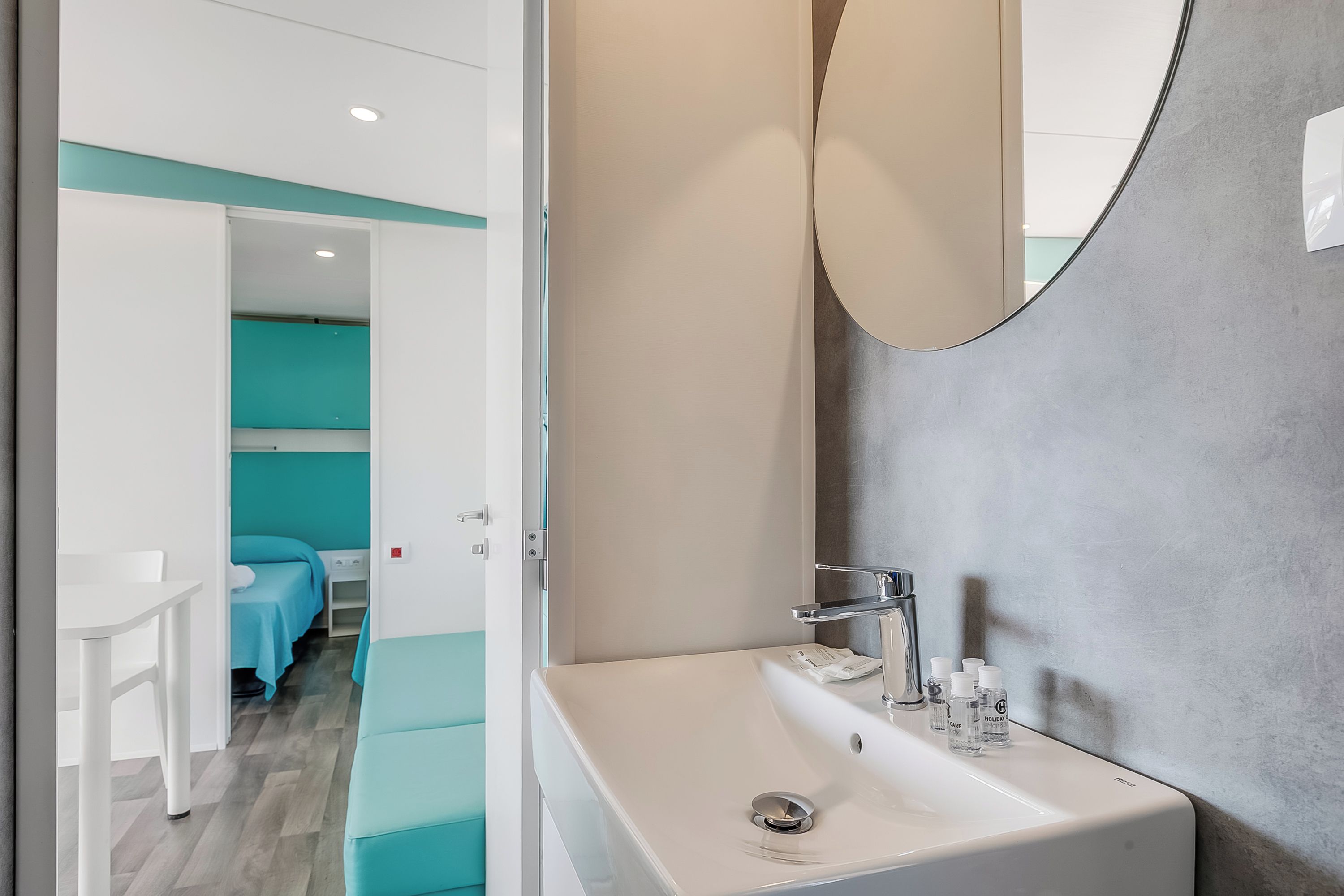A modern bathroom with a sink, mirror, and toiletries.