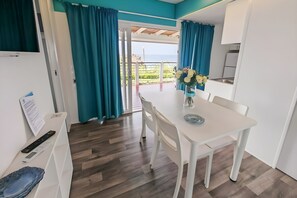 A modern kitchen with white cabinets, a dining area with a white table and chairs, and a view of the sea through a glass door. - Sea View - 40 Parallelo - Premium 14, Marina di Camerota, Italy (Marina di Camerota)