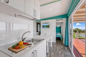 Une cuisine moderne équipée d’un évier, d’une planche à découper avec des légumes, et d’un coin repas comprenant une table et des chaises.