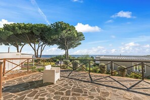 A stone patio with a white chair and a metal railing overlooking a body of water. - Sea View - 40 Parallelo - Superior 13, Marina di Camerota, Italy (Marina di Camerota)