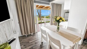 A modern kitchen with white cabinets, a dining table with chairs, and a view of the sea through the open door. - Sea View - 40 Parallelo - Superior 13, Marina di Camerota, Italy (Marina di Camerota)