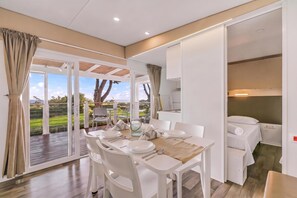 A dining area with a table set for four, a view of the outdoors, and a separate room with a bed. - Sea View - 40 Parallelo - Superior 12, Marina di Camerota, Italy (Marina di Camerota)