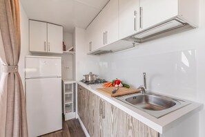 A compact kitchen with white cabinetry, a built-in stove, and a stainless steel sink. - Sea View - 40 Parallelo - Superior 12, Marina di Camerota, Italy (Marina di Camerota)
