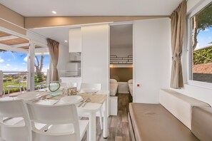 Un intérieur moderne comprenant un coin repas, une kitchenette et un espace nuit avec des lits superposés.