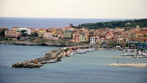 A coastal town with colorful buildings, a marina with boats, and a rocky breakwater. - Sea View - 40 Parallelo - Superior 12, Marina di Camerota, Italy (Marina di Camerota)