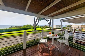 A covered outdoor seating area with a table and chairs, overlooking a landscaped garden and the sea. - Sea View - 40 Parallelo - Superior 12, Marina di Camerota, Italy (Marina di Camerota)