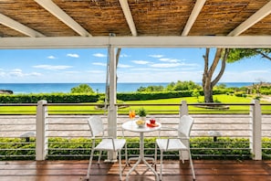 A covered outdoor seating area with a view of the sea and a well-maintained garden. - Sea View - 40 Parallelo - Superior 12, Marina di Camerota, Italy (Marina di Camerota)