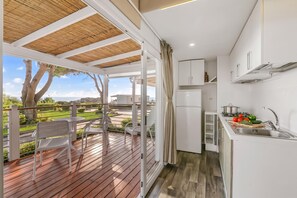 Une cuisine compacte avec vue sur l’extérieur, un coin repas avec des chaises et une terrasse en bois.