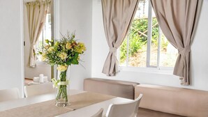 A dining area with a table, chairs, a vase of flowers, and a view through the window. - Sea View - 40 Parallelo - Superior 12, Marina di Camerota, Italy (Marina di Camerota)