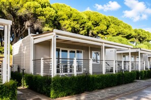 A row of modern, single-story cabins with large windows, a covered outdoor area, and a stone-paved pathway. - Sea View - 40 Parallelo - Superior 12, Marina di Camerota, Italy (Marina di Camerota)