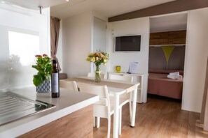 A modern hotel room with a dining area, a bed, a TV, and a small table with a vase of flowers. - Sea View - 40 Parallelo - Superior 11, Marina di Camerota, Italy (Marina di Camerota)