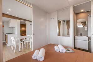A hotel room with a dining area, a bathroom, and a bed with towels. - Sea View - 40 Parallelo - Superior 11, Marina di Camerota, Italy (Marina di Camerota)