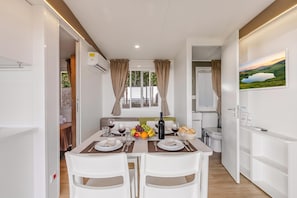 A modern dining area with a table set for two, a fruit bowl, and a bottle of wine. - Sea View - 40 Parallelo - Superior 11, Marina di Camerota, Italy (Marina di Camerota)