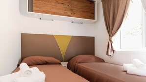 A hotel room with two beds, a wooden headboard, a window with curtains, and towels on the beds. - Sea View - 40 Parallelo - Superior 11, Marina di Camerota, Italy (Marina di Camerota)