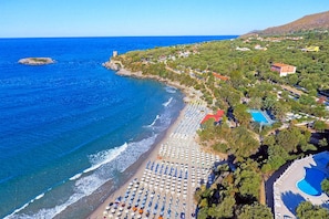 Vue aérienne d’une zone côtière comprenant une plage, une piscine et un ensemble de bâtiments.