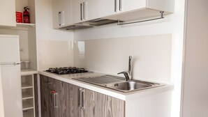 Eine moderne Küche mit weißen Schränken, einer Edelstahlspüle und einem Gasherd.
