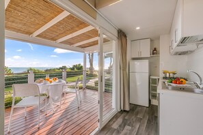 A modern kitchen with a view of the sea, a dining area with a table and chairs, and a wooden deck. - Sea View - 40 Parallelo - Superior 10, Marina di Camerota, Italy (Marina di Camerota)