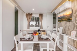 A dining area with a table set for two, a bottle of wine, and a plate of fruit. - Sea View - 40 Parallelo - Superior 10, Marina di Camerota, Italy (Marina di Camerota)