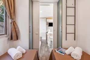 A hotel room with two beds, a window with curtains, a door leading to a bathroom, and a small table with a magazine. - Sea View - 40 Parallelo - Superior 10, Marina di Camerota, Italy (Marina di Camerota)