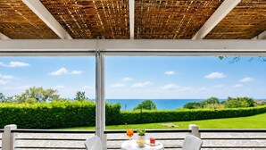 A terrace with a table and chairs overlooking a scenic view of the sea.