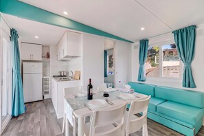 A modern kitchenette with a gas stove, a sink, and cabinets. There is a dining area with a table set for two, a sofa, and a window with curtains. - Sea View - 40 Parallelo - Superior 8, Marina di Camerota, Italy (Marina di Camerota)
