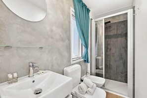 A modern bathroom with a white sink, toilet, and bidet, a glass shower enclosure, and a teal curtain. - Sea View - 40 Parallelo - Deluxe 7, Marina di Camerota, Italy (Marina di Camerota)