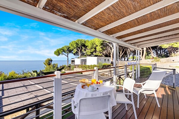 A covered outdoor seating area with a table set for two, overlooking a scenic view of the sea and trees. - Sea View - 40 Parallelo - Deluxe 7, Marina di Camerota, Italy (Marina di Camerota)