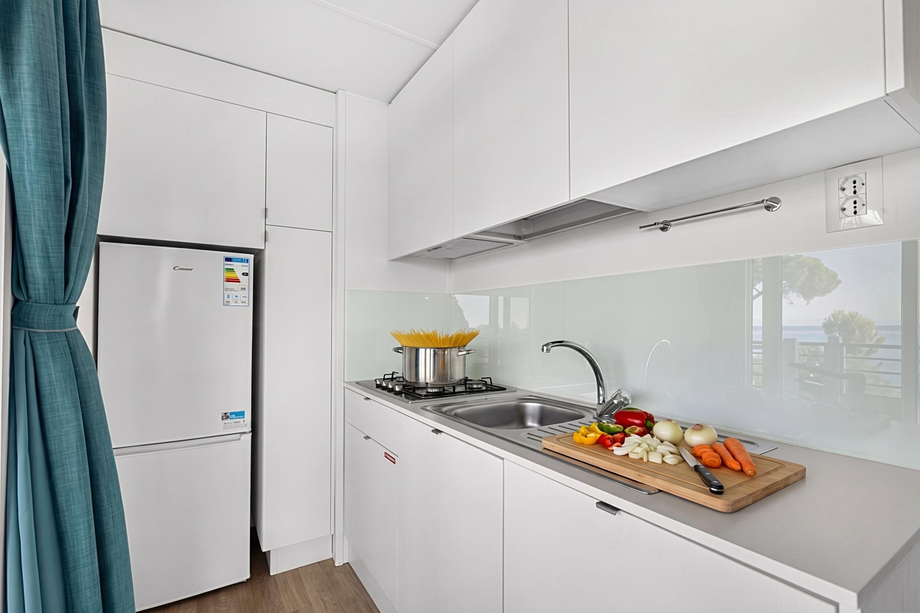 Une cuisine moderne avec des meubles blancs, un évier en acier inoxydable et une cuisinière.