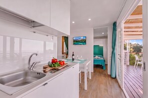 Eine moderne Küche mit Spüle, ein Essbereich mit Tisch für zwei Personen und Blick auf eine Berglandschaft durch ein Fenster.