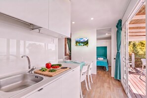 Une cuisine moderne équipée d’un évier, d’une planche à découper avec des légumes, et d’un coin repas comprenant une table et des chaises.