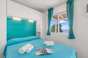Une chambre à coucher avec un lit, une fenêtre avec des rideaux et un magazine sur le lit.