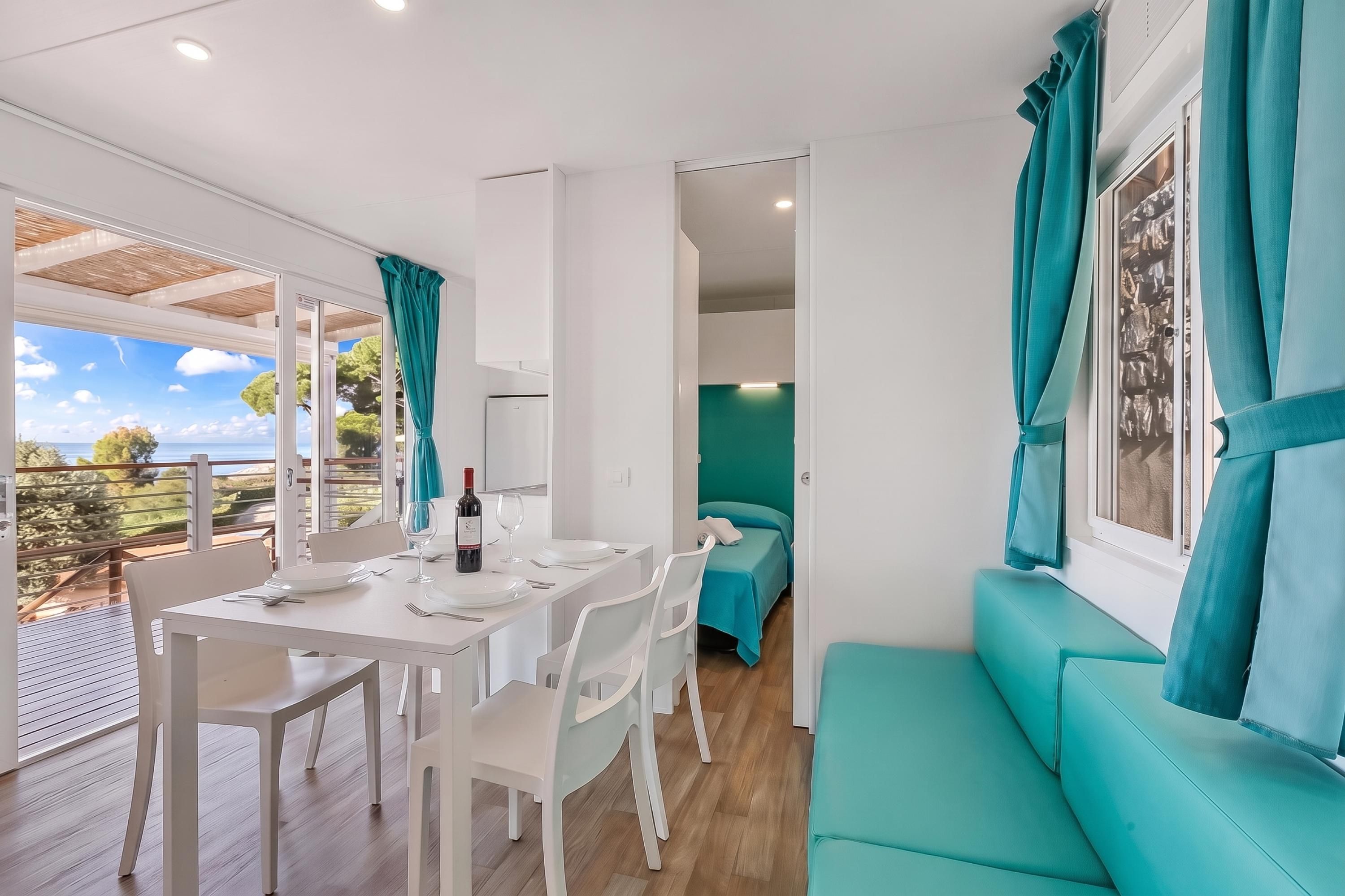 A modern interior with a dining area, a sofa, and a view of the outdoors.