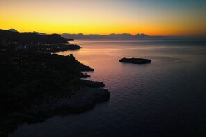 A coastal landscape with a calm sea, rocky coastline, and distant mountains during sunset. - Sea View - 40 Parallelo - Deluxe 5, Marina di Camerota, Italy (Marina di Camerota)