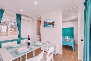 A modern, well-lit room with a dining area, a bed with a view, and a mounted picture of a mountain landscape. - Sea View - 40 Parallelo - Deluxe 5, Marina di Camerota, Italy (Marina di Camerota)